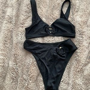 Black swimsuit with a gold ring in the center and on the bottoms